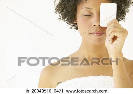 Young woman holding a card over her eye View Large Photo Image Stock Image - Young woman holding a card over her eye. Fotosearch