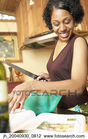Young woman holding a knife in a kitchen View Large Photo Image Stock Image - Young woman holding a knife in a kitchen. Fotosearch