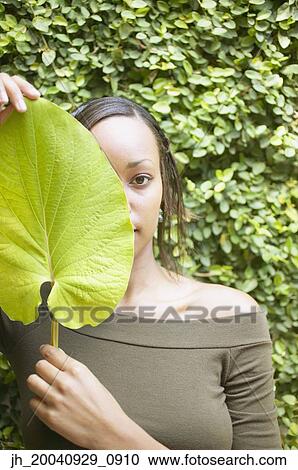 Young woman holding a leaf in front of her face View Large Photo Image Stock Image - Young woman holding a leaf in front of her face. Fotosearch