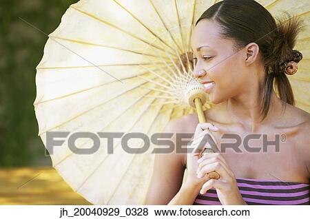 Stock Photo - Young woman holding a parasol smiling. Fotosearch