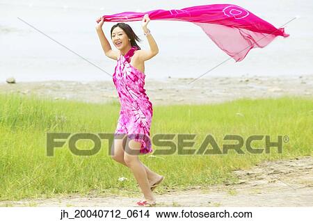 Young woman holding a sarong over her head running View Large Photo Image Picture - Young woman holding a sarong over her head running. Fotosearch