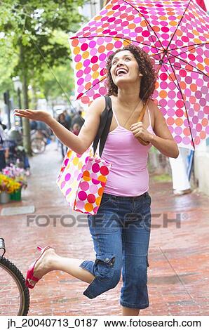 Young woman holding an umbrella laughing in the rain View Large Photo Image Stock Photo - Young woman holding an umbrella laughing in the rain. Fotosearch