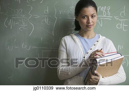 Stock Photo - Young woman holding backs standing in a classroom. Fotosearch