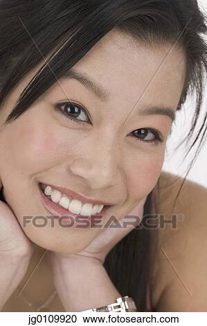 Stock Image - Young woman looking at camera smiling. Fotosearch