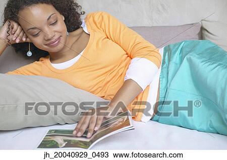 Young woman lying down reading a book View Large Photo Image Stock Image - Young woman lying down reading a book. Fotosearch