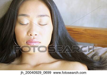 Young woman lying on a bed with her eyes closed View Large Photo Image Stock Photo - Young woman lying on a bed with her eyes closed. Fotosearch