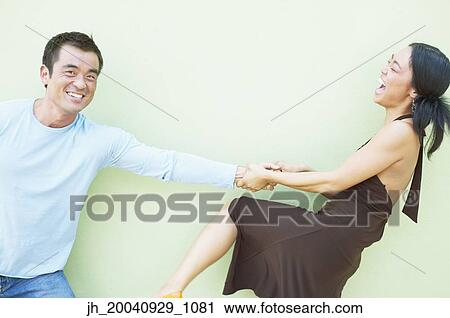 Young woman pulling a mid adult man by his arm View Large Photo Image Stock Image - Young woman pulling a mid adult man by his arm. Fotosearch