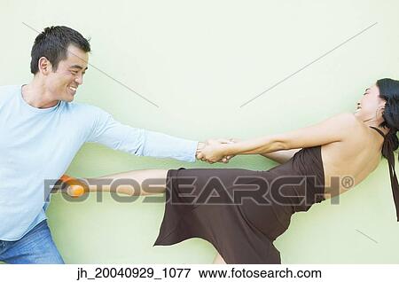 Young woman pulling a mid adult man by his arm View Large Photo Image Stock Photo - Young woman pulling a mid adult man by his arm. Fotosearch