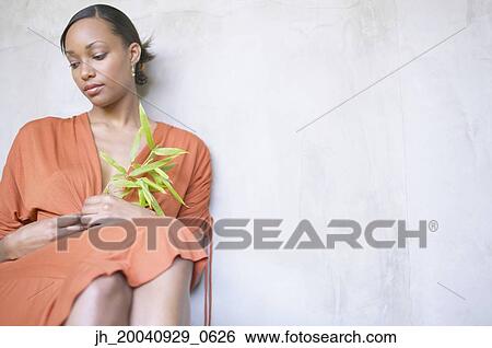 Young woman sitting holding a plant View Large Photo Image Stock Photograph - Young woman sitting holding a plant. Fotosearch