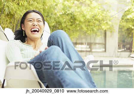 Young woman sitting on a chair outdoors laughing View Large Photo Image Stock Image - Young woman sitting on a chair outdoors laughing. Fotosearch