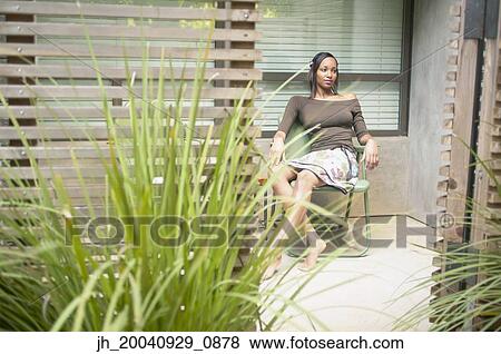 Young woman sitting on a chair outdoors View Large Photo Image Stock Photo - Young woman sitting on a chair outdoors. Fotosearch