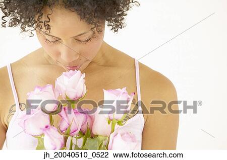 Stock Image - Young woman smelling roses. Fotosearch