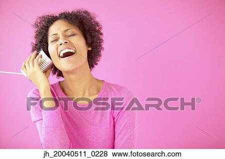 Young woman smiling holding a can with a string to her ear View Large Photo Image Stock Photo - Young woman smiling holding a can with a string to her ear. Fotosearch
