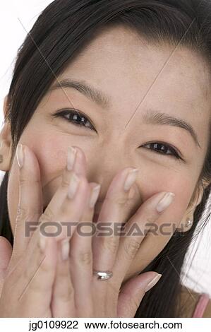 Young woman smiling with her hands on her mouth View Large Photo Image Stock Image - Young woman smiling with her hands on her mouth. Fotosearch