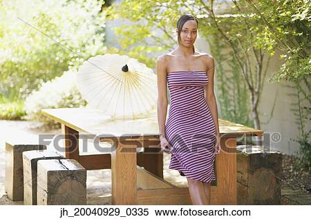 Young woman standing against a table View Large Photo Image Stock Photography - Young woman standing against a table. Fotosearch