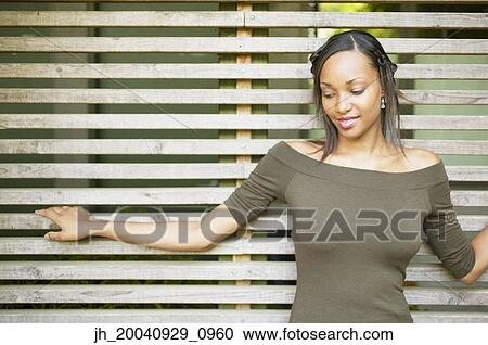Young woman standing against a wooden structure looking down View Large Photo Image Stock Image - Young woman standing against a wooden structure looking down. Fotosearch