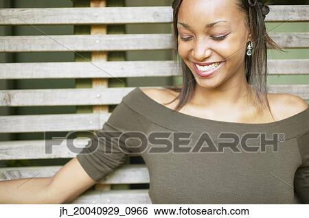 Young woman standing against a wooden structure smiling View Large Photo Image Stock Photograph - Young woman standing against a wooden structure smiling. Fotosearch