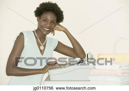 Stock Photograph - Young woman standing at a cash register. Fotosearch