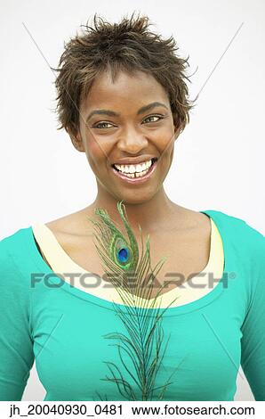 Young woman standing holding a peacock feather smiling View Large Photo Image Stock Image - Young woman standing holding a peacock feather smiling. Fotosearch