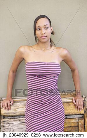 Young woman standing leaning against a table View Large Photo Image Stock Photo - Young woman standing leaning against a table. Fotosearch