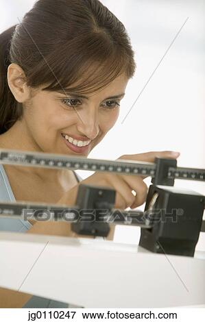 Young woman standing on a weighing scale View Large Photo Image Stock Photo - Young woman standing on a weighing scale. Fotosearch