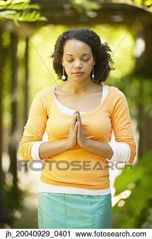 Young woman standing with her hands together and eyes closed View Large Photo Image Stock Image - Young woman standing with her hands together and eyes closed. Fotosearch