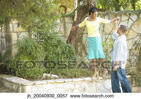 Young woman walking on a wall holding a young man's hand View Large Photo Image Stock Photo - Young woman walking on a wall holding a young man's hand. Fotosearch