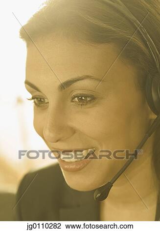 Young woman wearing a headset smiling View Large Photo Image Stock Image - Young woman wearing a headset smiling. Fotosearch