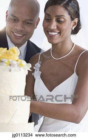 Bride and groom looking at their wedding cake View Large Photo Image Picture - Bride and groom looking at their wedding cake. Fotosearch