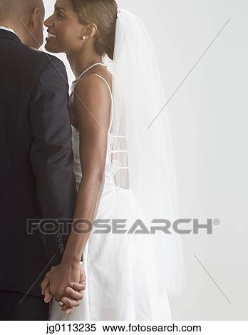 Stock Photography - Bride whispering into a groom's ears. Fotosearch