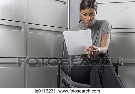 Businesswoman sitting on a chair reading View Large Photo Image Stock Image - Businesswoman sitting on a chair reading. Fotosearch