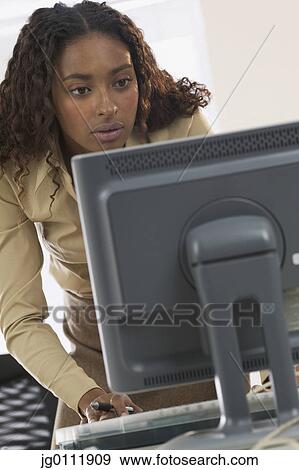 Stock Photo - Businesswoman using a computer at the office. Fotosearch