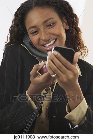 Close-up of a businesswoman applying make up talking on a landline phone View Large Photo Image Stock Photo - Close-up of a businesswoman applying make up talking on a landline phone. Fotosearch
