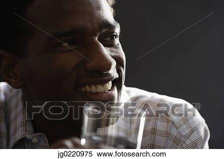 Close-up of a mid adult man holding a glass of water smiling View Large Photo Image Stock Photography - Close-up of a mid adult man holding a glass of water smiling. Fotosearch