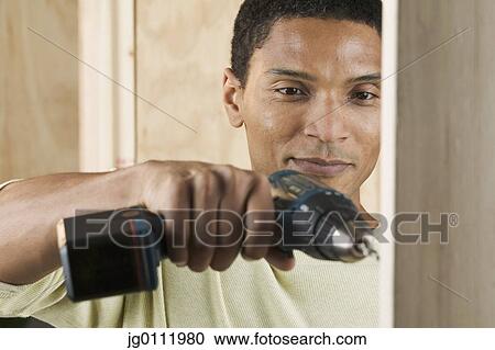 Close-up of a mid adult man using a drilling machine View Large Photo Image Stock Image - Close-up of a mid adult man using a drilling machine. Fotosearch