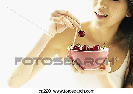Close-up of a young woman eating a cherry View Large Photo Image Stock Image - Close-up of a young woman eating a cherry. Fotosearch