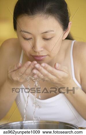 Stock Photo - Close-up of a young woman washing her face. Fotosearch