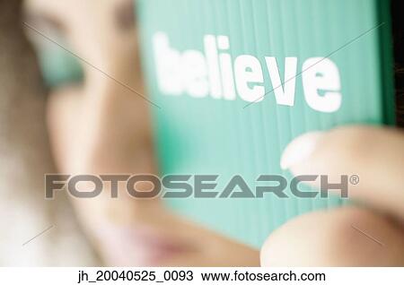Stock Image - Close-up of young woman holding a card up with her eyes closed. Fotosearch