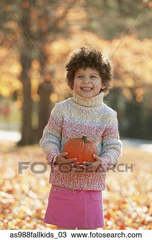 Stock Image - Girl holding a pumpkin smiling. Fotosearch
