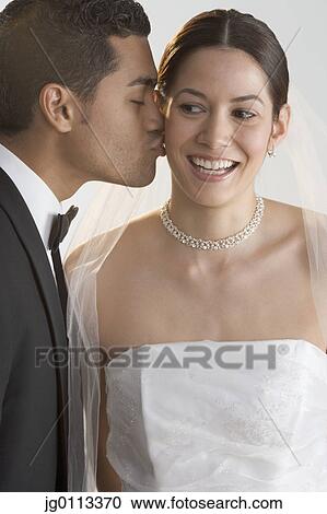 Stock Image - Groom kissing his bride. Fotosearch