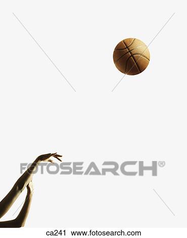 Stock Image - Low angle view of a young woman playing basketball. Fotosearch