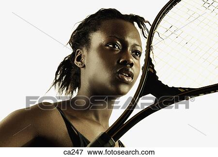 Stock Photo - Low angle view of a young woman with a tennis racket. Fotosearch
