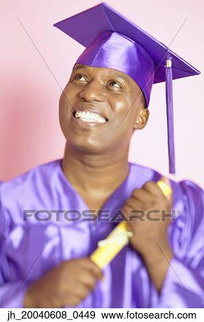 Male graduate smiling holding a degree View Large Photo Image Stock Photo - Male graduate smiling holding a degree. Fotosearch