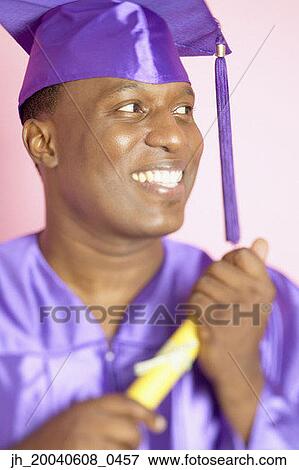 Male graduate smiling holding a degree View Large Photo Image Stock Photo - Male graduate smiling holding a degree. Fotosearch