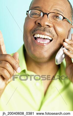 Stock Image - Mature man talking on mobile phone smiling. Fotosearch