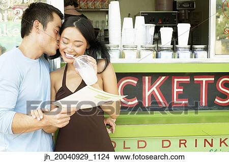 Mid adult man and a young woman standing at a food and drinks stall View Large Photo Image Picture - Mid adult man and a young woman standing at a food and drinks stall. Fotosearch