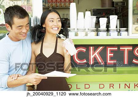 Mid adult man and a young woman standing at a food and drinks stall View Large Photo Image Stock Image - Mid adult man and a young woman standing at a food and drinks stall. Fotosearch