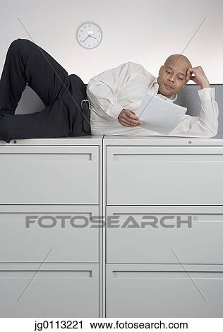 Stock Image - Mid adult man lying on his side. Fotosearch