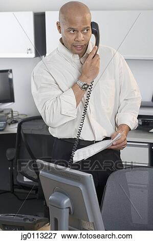 Stock Photo - Mid adult man talking on a landline phone. Fotosearch