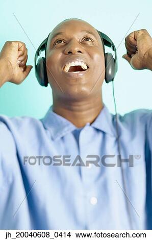 Mid adult man wearing headphones looking up View Large Photo Image Picture - Mid adult man wearing headphones looking up. Fotosearch